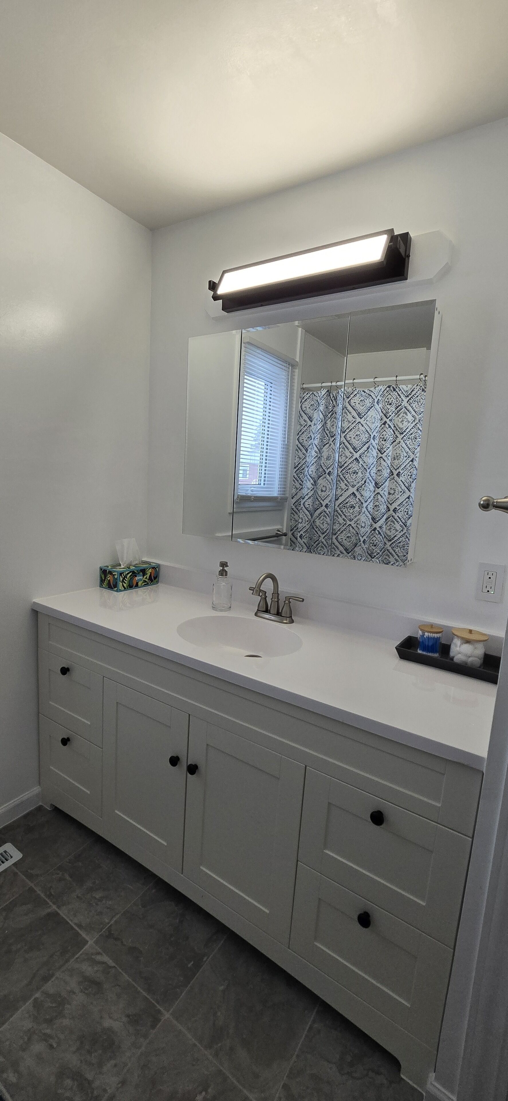A bathroom with a white vanity, a mirror, a sink, and a shower curtain.