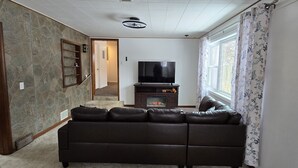 Uma sala de estar com lareira, sofá, televisão e escada que dá acesso a outro cômodo.