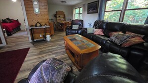 A cozy living room with a leather sofa, a wooden coffee table, and a red bed in the corner. - Private 3-bedroom farmhouse in Rural Roseau (Roseau)