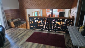 A cozy room with wooden walls and a red carpet. A wooden bench with a carved backrest is in the center. - Private 3-bedroom farmhouse in Rural Roseau (Roseau)