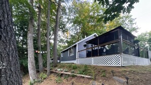 Ein modernes Haus mit einem großen Glasfenster, umgeben von Bäumen und einer Holzterrasse.