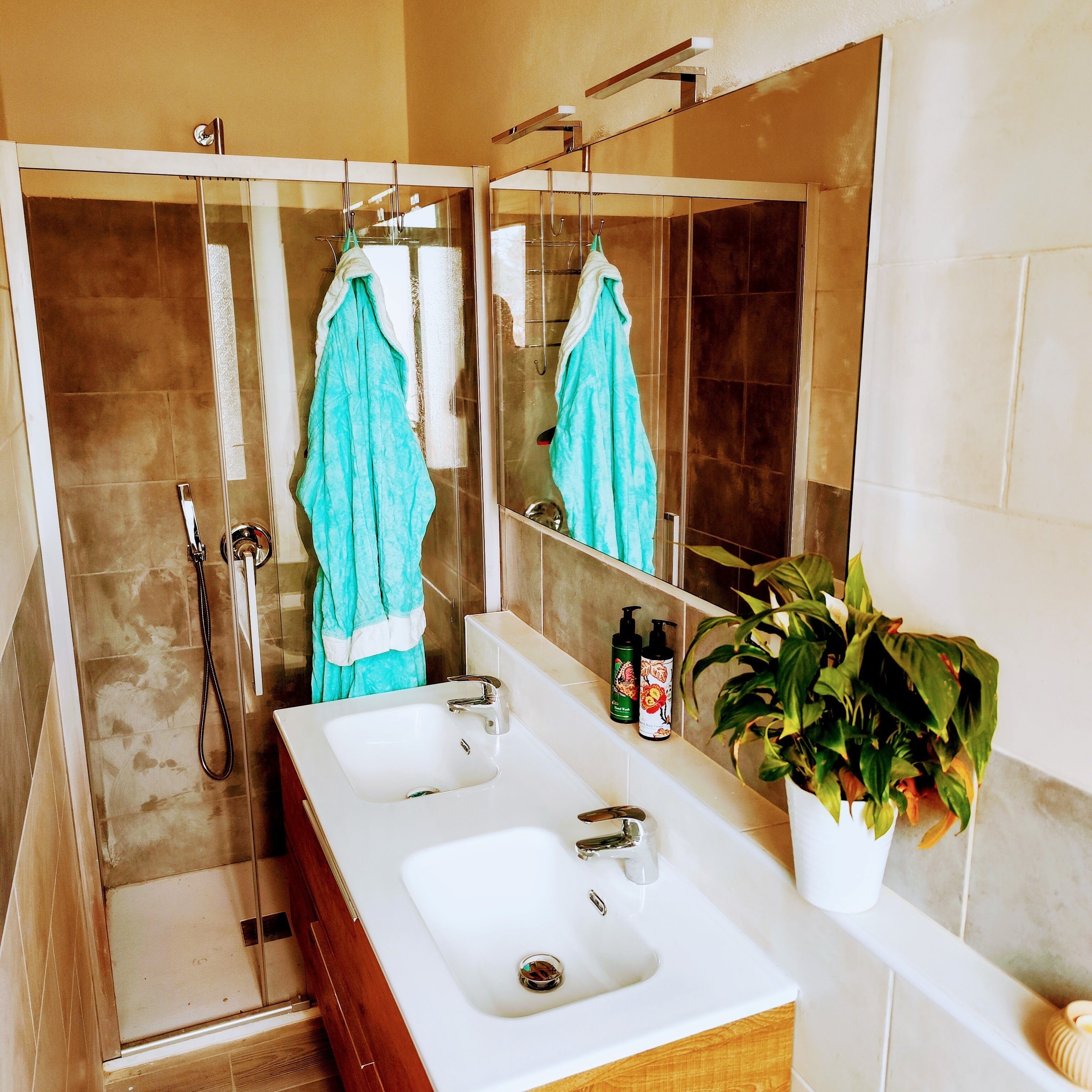 A bathroom with two sinks, a shower, and a large mirror.