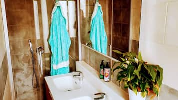 A bathroom with two sinks, a shower, and a large mirror.