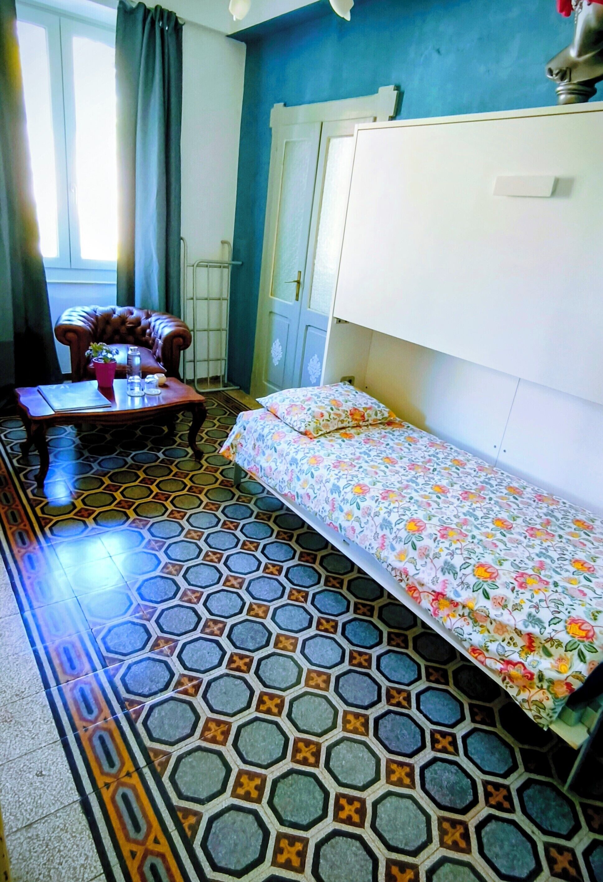 Una stanza con un letto, un divano, un tavolo con una pianta e una finestra con tende.