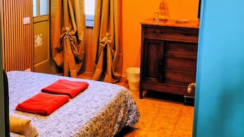 A bedroom with a bed, curtains, a dresser, a framed picture, and a door with a number.