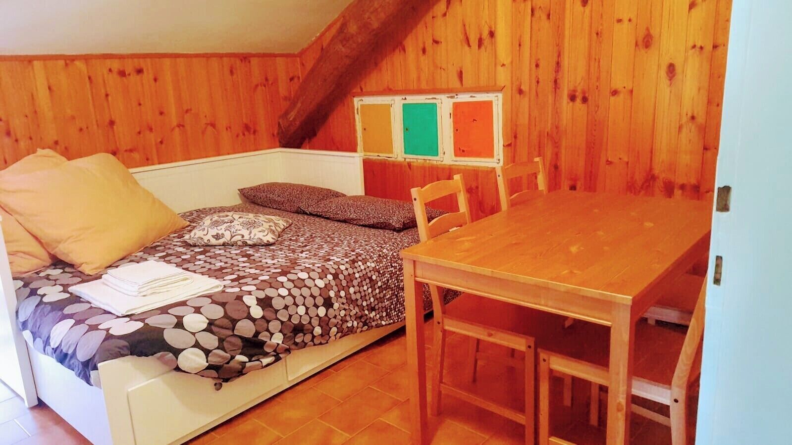 A cozy room with a bed, a wooden table, and a bench.
