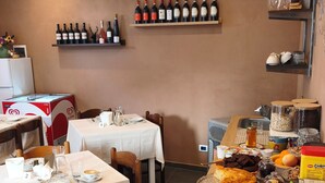 Un restaurant amb taules preparades per dinar, una selecció de botelles de vi a l'estant i diversos plats al mostrador.