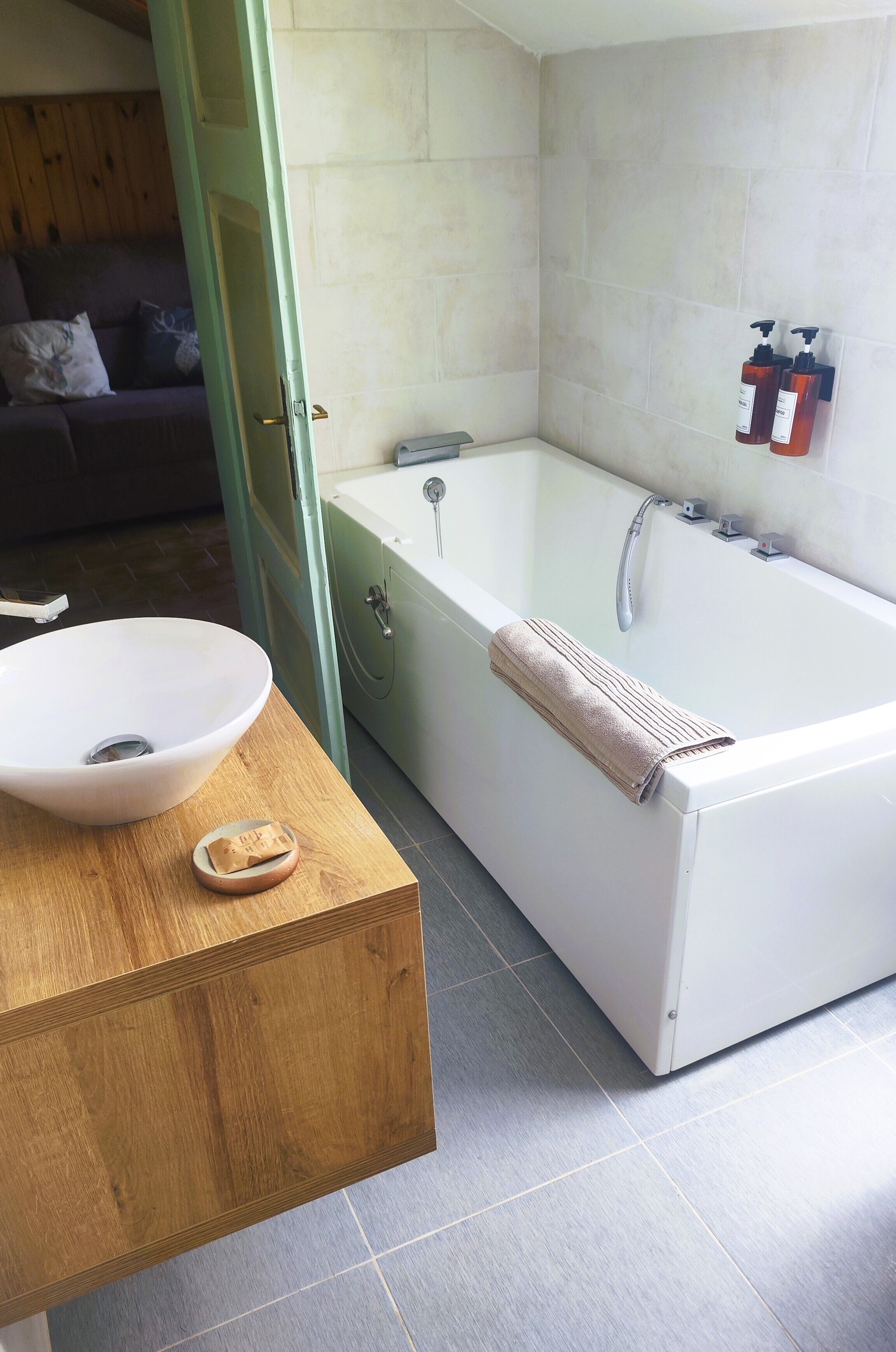 A bathroom with a white bathtub, a wooden vanity with a sink, and a towel rack.