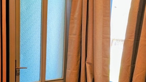 Una porta amb vidres gravats i un disseny floral decoratiu, cortines arreplegades i un sòl amb moqueta.