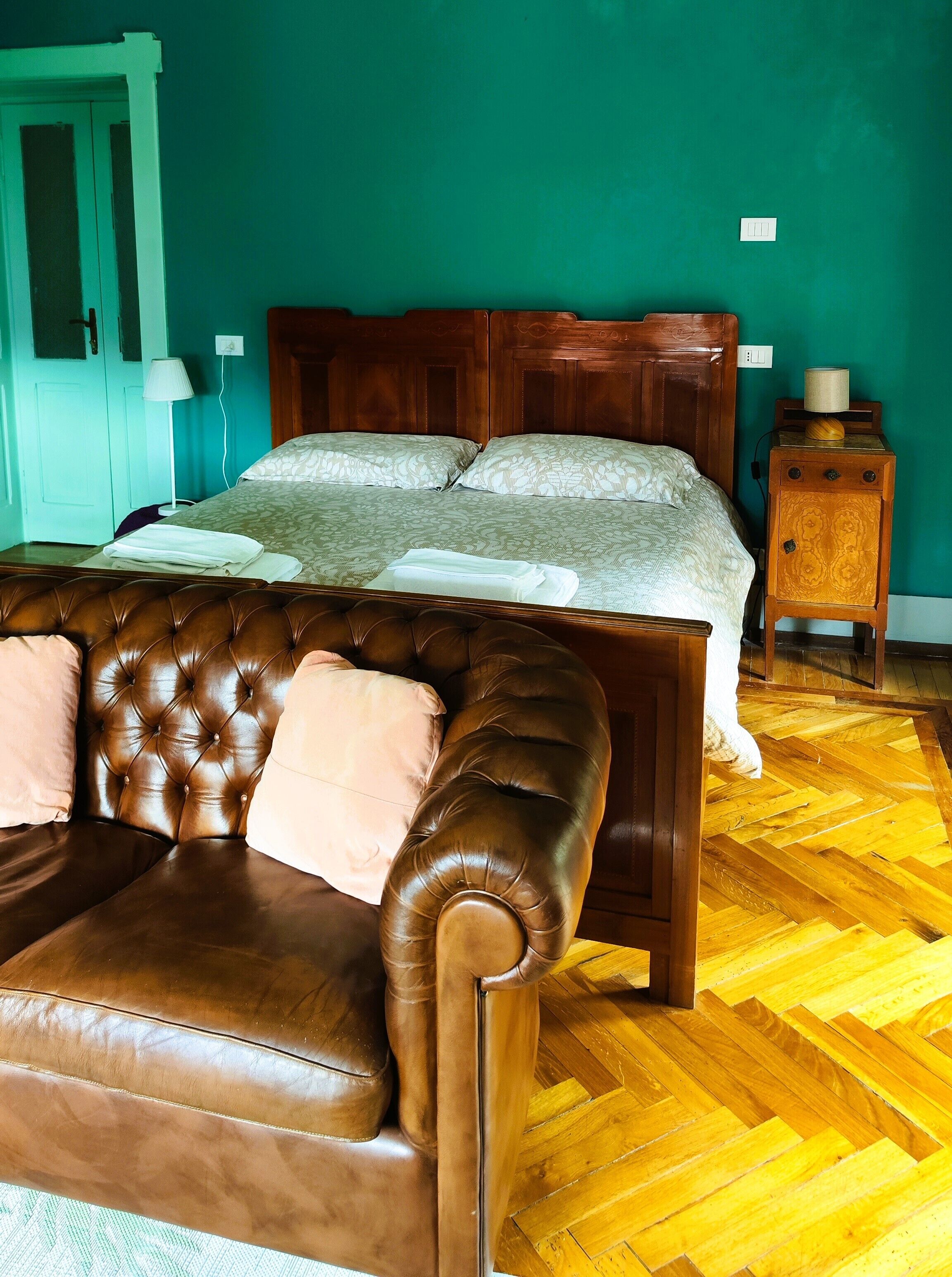 Une chambre à coucher avec un lit en bois, un canapé en cuir marron et une table de chevet en bois avec une lampe.