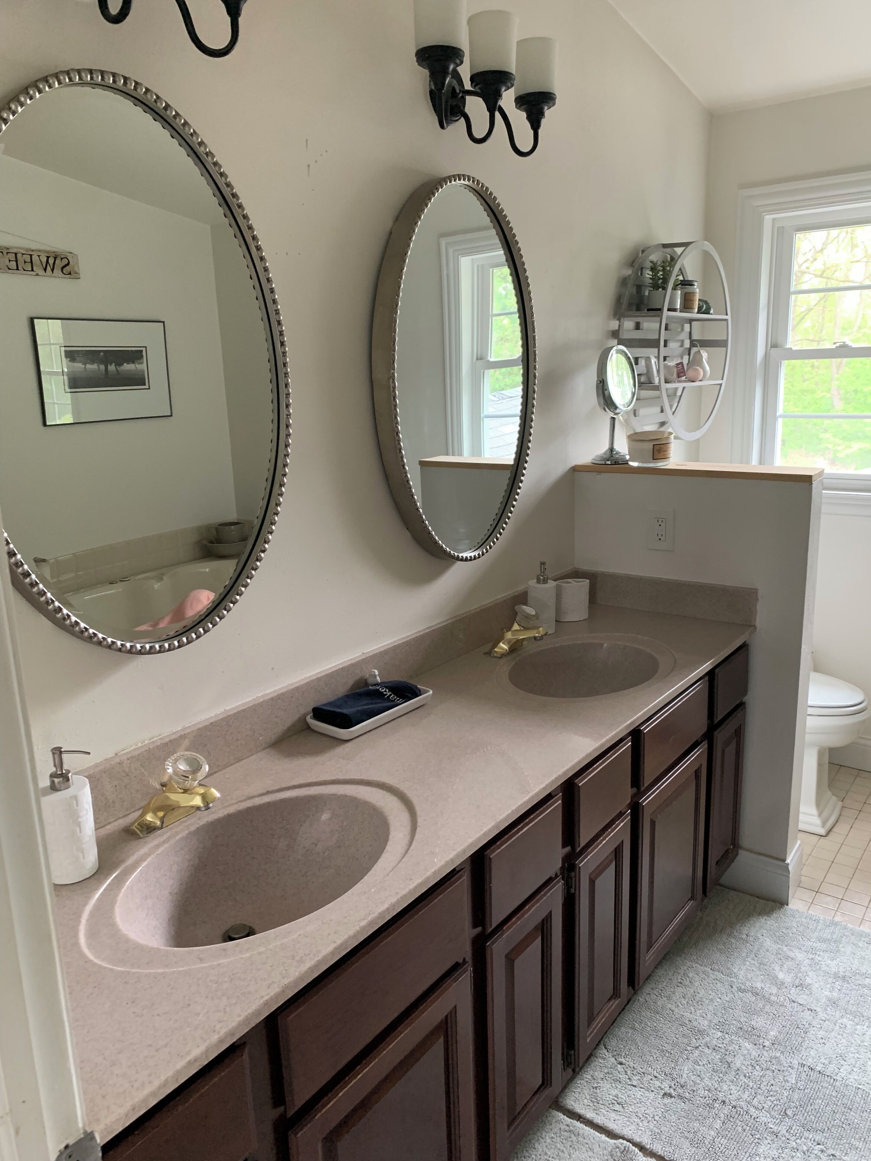 A bathroom with two sinks, a large mirror, and a vanity with a shelf.