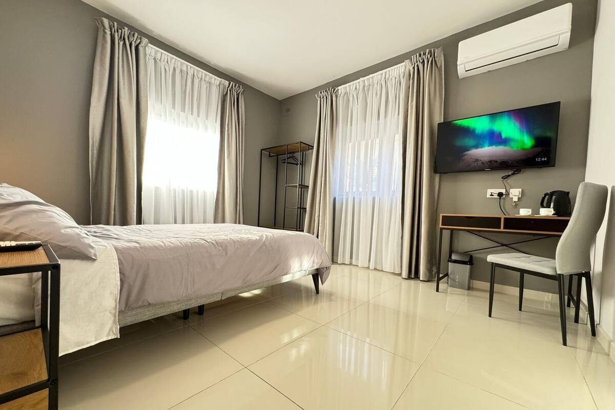 Ein modernes Hotelzimmer mit Bett, Schreibtisch, Stuhl, Fernseher und Kleiderschrank.