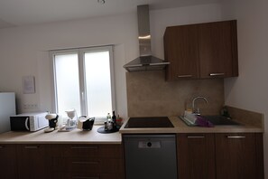 A modern kitchen with a dishwasher, a coffee maker, and a kettle on the counter. - L'émeraude, appartement standing au coeur de la verdure (Vence)