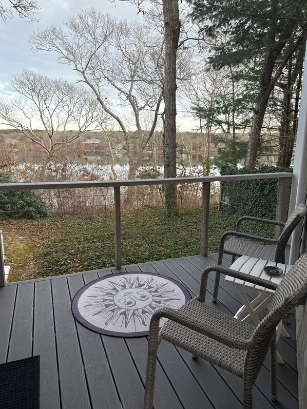 A wooden deck with wicker chairs and a round table with a sun design.