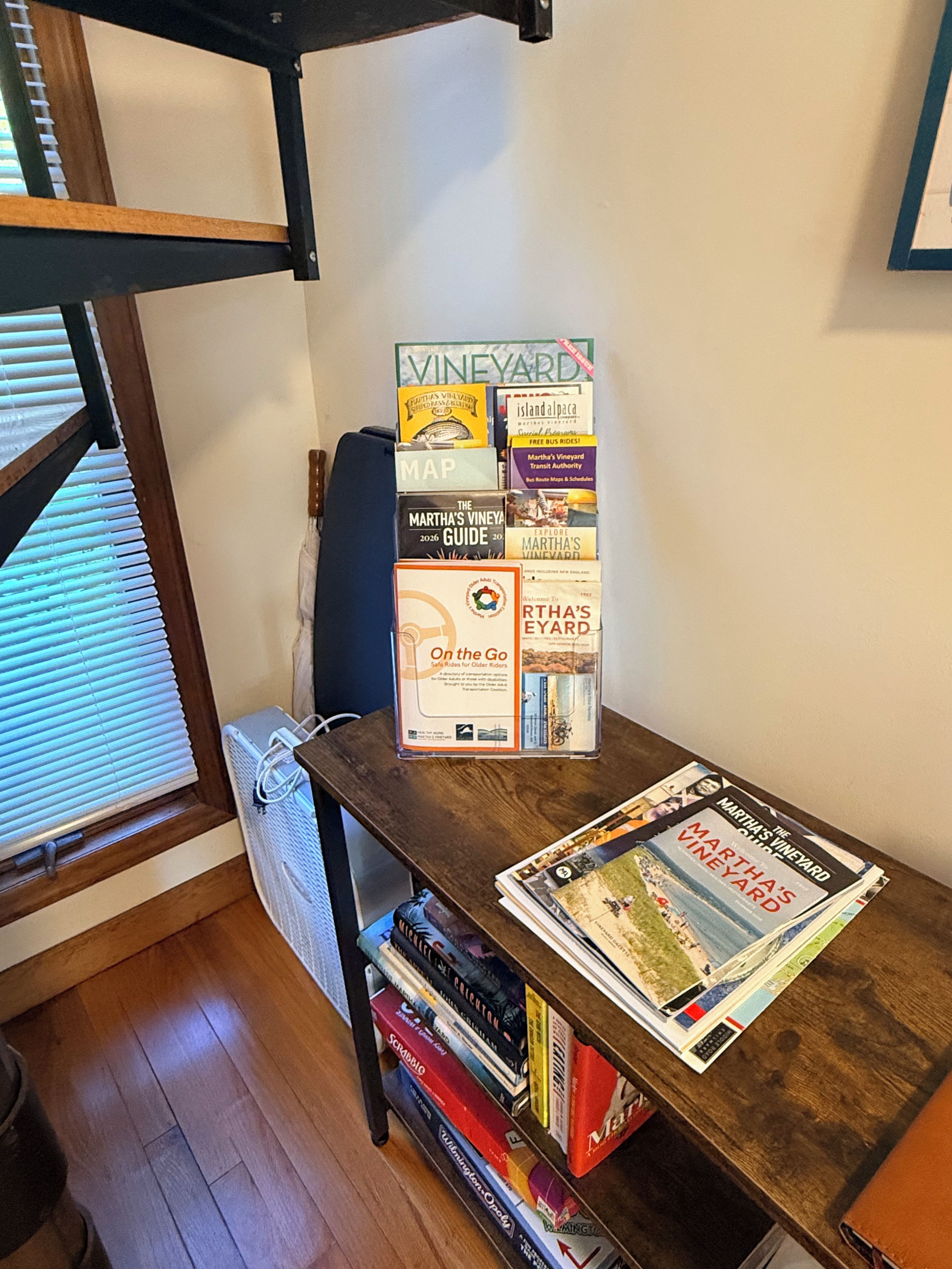 A wooden table with a stack of books and magazines, including a 'VINEYARD' guide and a 'Martha's Vineyard' magazine.