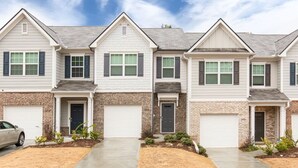 A row of townhouses with brick accents, white siding, and dark shutters. Each house has a garage door and a small front yard with shrubs. - A Traveler’s dream; Private Townhome 15min to Airport in peaceful Union City (Union City)
