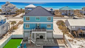 Une propriété située en bord de mer, comprenant une maison à deux étages, un patio couvert et une piscine.