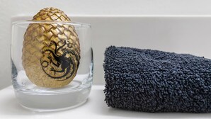 A clear glass container with a golden object, possibly a decorative item, and a dark textured towel. - Dreamfyre's Ancient Dragon Horn Suite (Seattle)