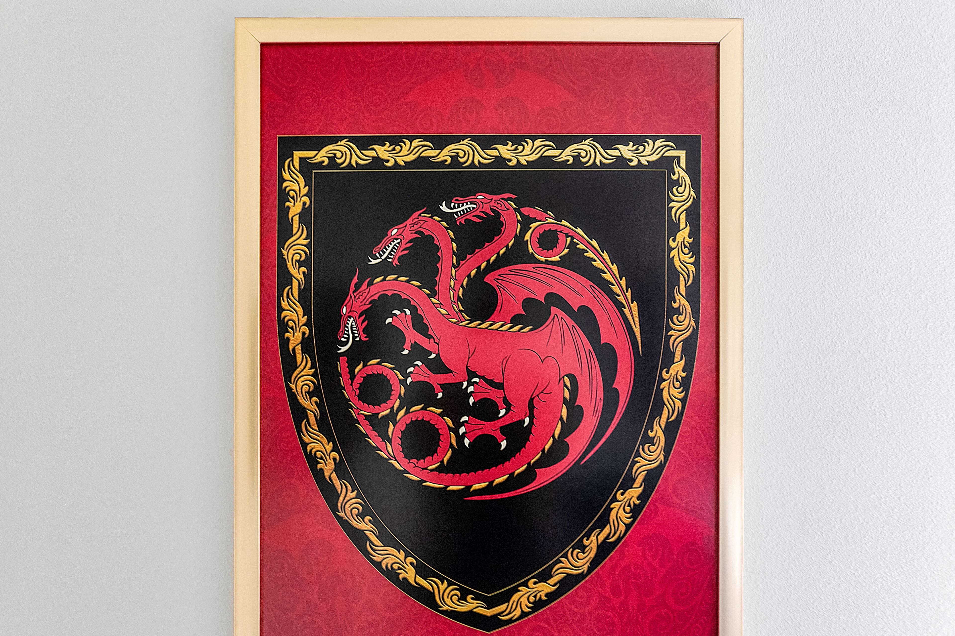 A framed emblem with a red and black design, surrounded by a gold ornate border.