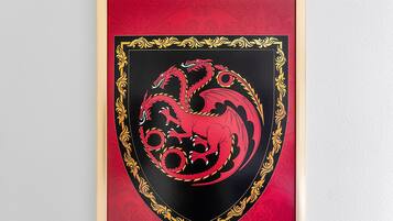 A framed emblem with a red and black design, surrounded by a gold ornate border.