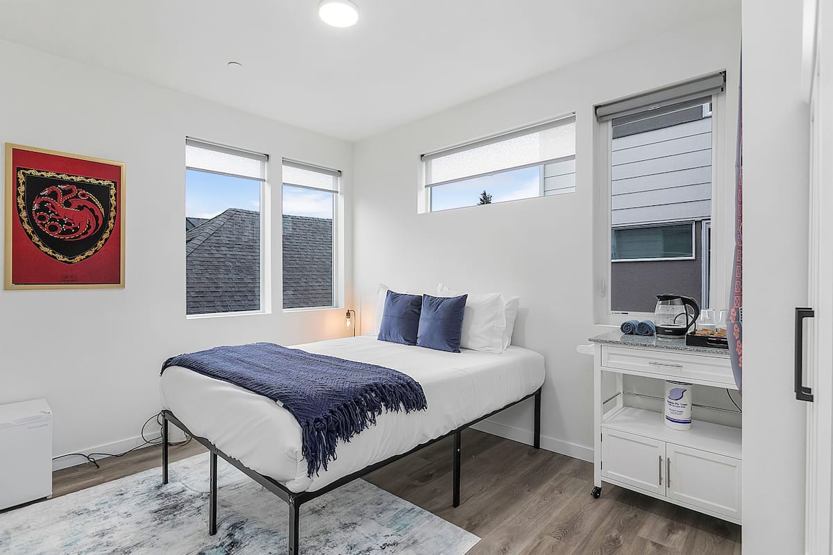 Un dormitorio con cama, escritorio, silla y ventana.