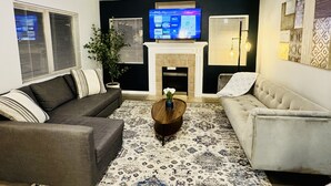 A living room with two sofas, a coffee table, a fireplace, and a TV mounted above it. - Charming 2-BHK Condo, nestled in the heart of picturesque Leavenworth. (Leavenworth)