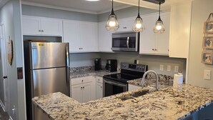 A modern kitchen with granite countertops, stainless steel appliances, and pendant lighting. - Seaside Retreat - Shore Drive, 3 bed, 2.5 bathrooms with an Ocean View. (Horry County)