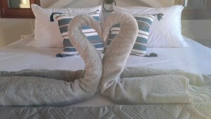 A bed with pillows arranged to form a heart shape, a blanket, and a quilted bedspread. - Dorothea Panoramic Villa is one of a kind—a hidden gem  of Paros.Asteria (Paros)