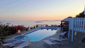 An infinity pool with lounge chairs and a view of the sea at sunset. - Dorothea Panoramic Villa is one of a kind—a hidden gem  of Paros.Asteria (Paros)