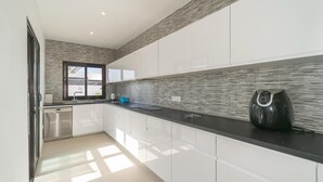 A modern kitchen with white cabinets, a black countertop, and a built-in stove. - Stunning 3 Bed 2 Bath Villa in Playa Blanca (Yaiza)