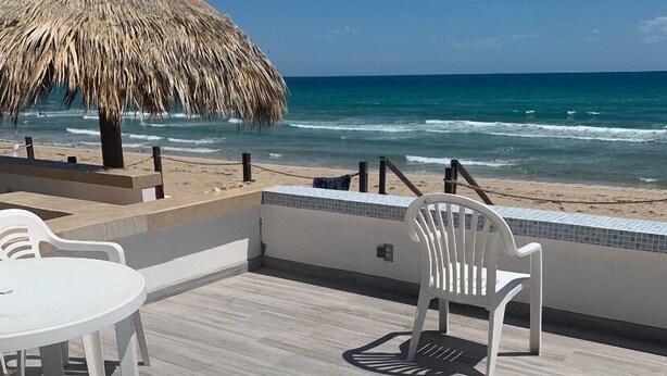 A beachside patio with white lounge chairs and a thatched umbrella, overlooking the ocean. - Beach Front Condo ❤️ in Peaceful Las Conchas🌴 WiFi, Sleeps 8  (Puerto Penasco)