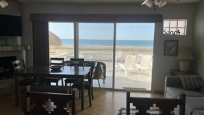 A living room with a dining area, a ceiling fan, and a view of the beach. - Beach Front Condo ❤️ in Peaceful Las Conchas🌴 WiFi, Sleeps 8  (Puerto Penasco)