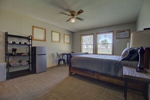A bedroom with a bed, a desk, a chair, a ceiling fan, and a window. - Cottage V |Studio Cottage | Lake & Beach |Water Sports! | Legacy Lakeside Resort (Clitherall)