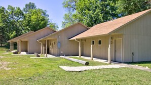 Une rangée de chalets de plain-pied, au design simple et fonctionnel, chacun doté d’un porche à l’avant et d’une porte.