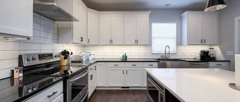 A modern kitchen with white cabinets, stainless steel appliances, and a large island.