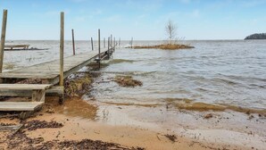 Een houten steiger die zich uitstrekt over een rustig wateroppervlak, met een zandstrand aan het einde.