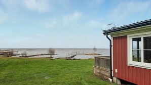 Een rood gebouw met een wit raam, een gazon en een waterpartij op de achtergrond.