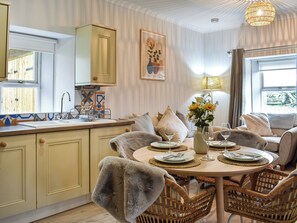 A dining area with a round table set for four, surrounded by wicker chairs. - Escape to tranquility in our charming 2-bed cottage in Woodhead of Mailer. (Woodhead of Mailer)