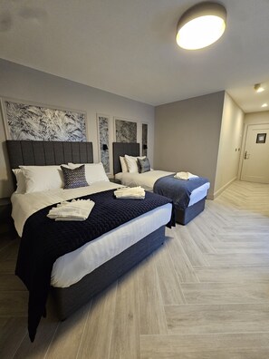 Een hotelkamer met twee bedden, een groot kunstwerk aan de muur en een houten vloer.