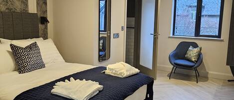 Un dormitorio moderno con una cama grande, una silla y una ventana.