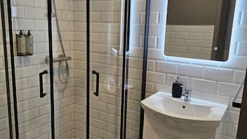 A bathroom with a glass-enclosed shower, a white sink, and a checkered floor.