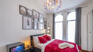 Een moderne hotelkamer met een groot bed, rode beddengoed, een minibar en uitzicht op de stad.
