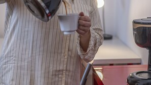 Iemand giet een drankje uit een waterkoker in een kop.
