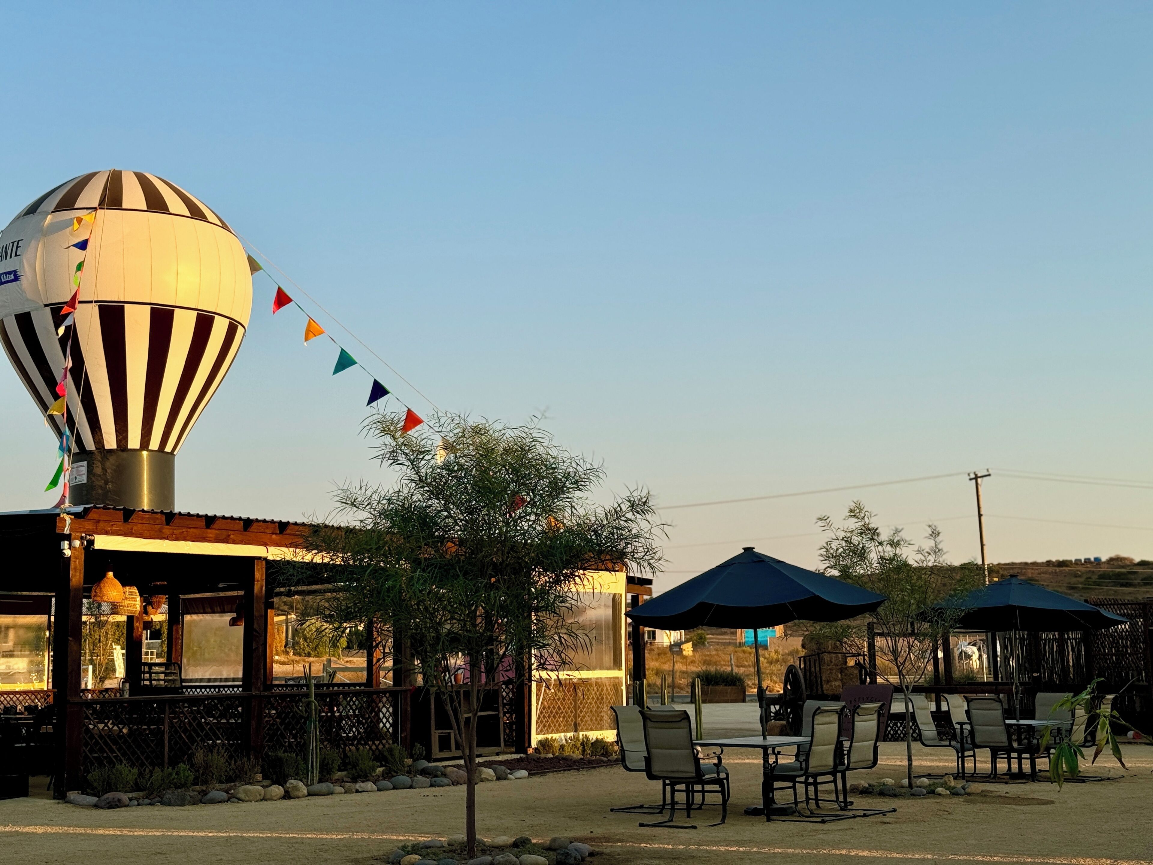 Un globo aerostático amarrado a un edificio con mesas y sombrillas al aire libre.
