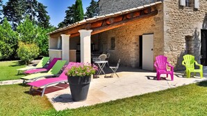 A stone building with a covered patio area, outdoor seating, and a grassy lawn. - Le Mazet De Bious Sadous (Isle Sur La Sorgue)