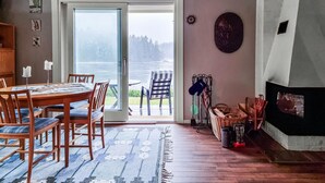 A dining area with a table and chairs, a fireplace, and a view through a glass door to an outdoor deck. - 3 bedroom gorgeous home in öxabäck (Öxabäck)