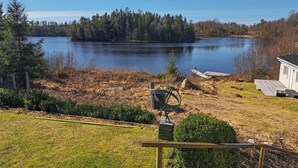 A lakeside property with a wooden deck, a small garden, and a view of a lake surrounded by trees. - 3 bedroom gorgeous home in öxabäck (Öxabäck)