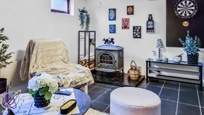 A cozy living room with a vintage stove, a comfortable chair, and a small table with decorative items. - 3 bedroom gorgeous home in öxabäck (Öxabäck)
