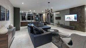 A modern living room with a dark blue sofa, a grey armchair, a small round table, and a flat-screen TV mounted on the wall. - Villa Aria with pool, 100m to beach (Tučepi)