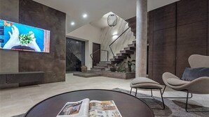 A modern living room with a large flat-screen TV, a round coffee table with magazines, a staircase, and a minimalist design. - Villa Aria with pool, 100m to beach (Tučepi)